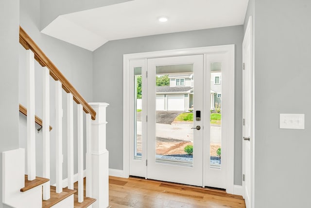 foyer entrance featuring light wood-type flooring, stairway, and baseboards