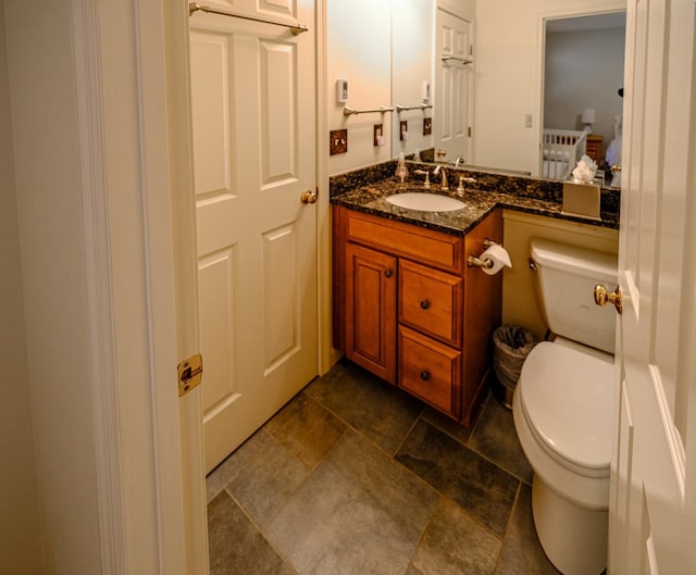 bathroom featuring stone finish floor, vanity, and toilet