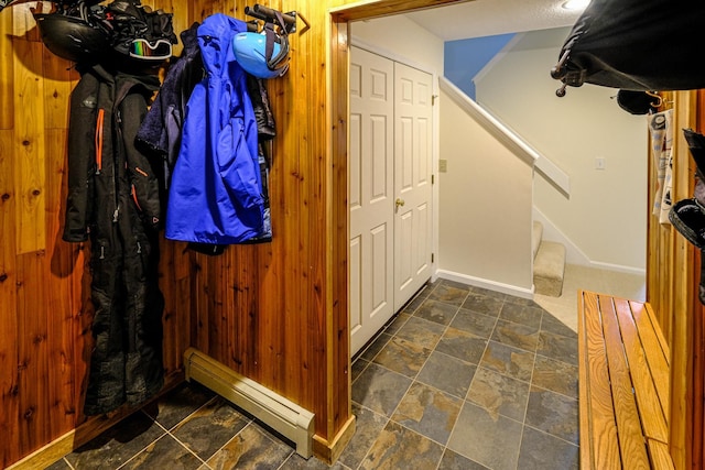 interior space with a baseboard heating unit, stone finish flooring, and wood walls