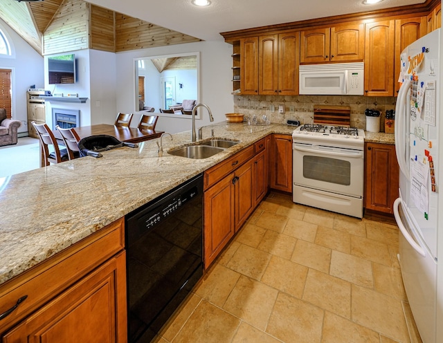 kitchen with tasteful backsplash, white appliances, a sink, and light stone counters