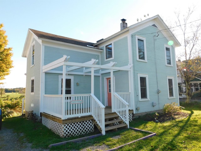 back of house featuring a chimney, a pergola, and a yard