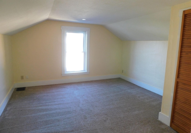 bonus room featuring lofted ceiling, carpet flooring, visible vents, and baseboards