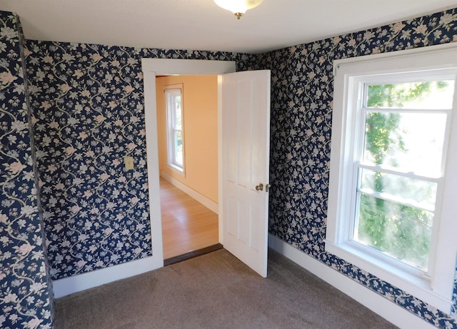 spare room with baseboards, carpet flooring, and wallpapered walls