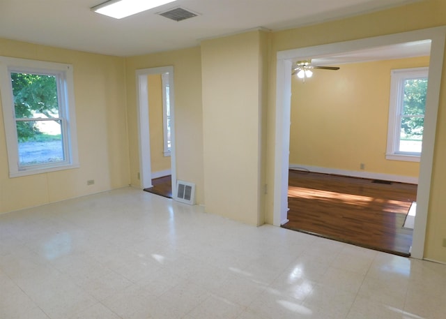 spare room featuring ceiling fan, light floors, and visible vents