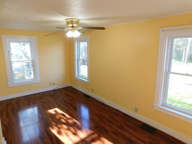 unfurnished room with visible vents, dark wood finished floors, baseboards, and ceiling fan