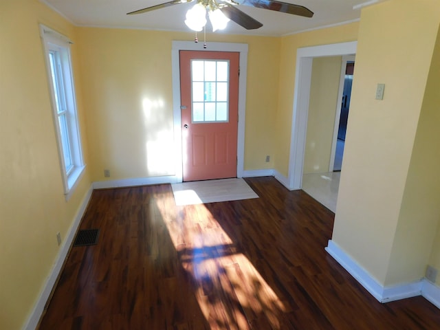 entryway featuring crown molding, dark wood finished floors, visible vents, and baseboards