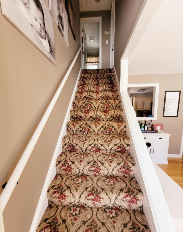 staircase featuring baseboards and wood finished floors