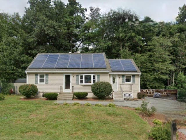 single story home with entry steps, a front yard, and roof mounted solar panels