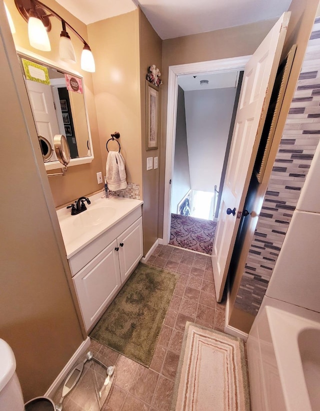 bathroom featuring a tub, vanity, and baseboards