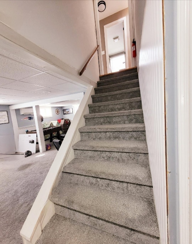 stairs with carpet and a drop ceiling