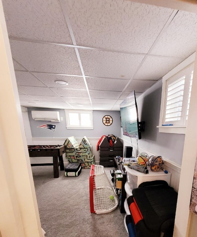 living area featuring a drop ceiling, carpet flooring, and a wall unit AC