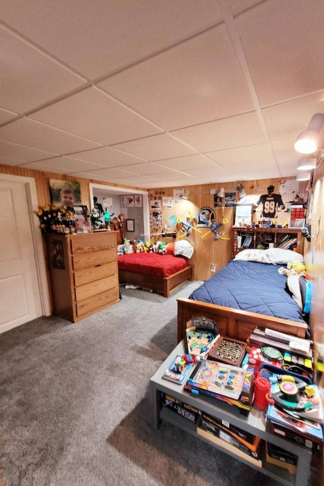 bedroom with a paneled ceiling, wooden walls, and carpet floors