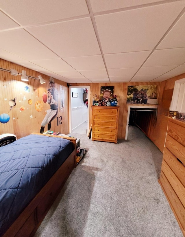 bedroom featuring wooden walls, a drop ceiling, and carpet floors