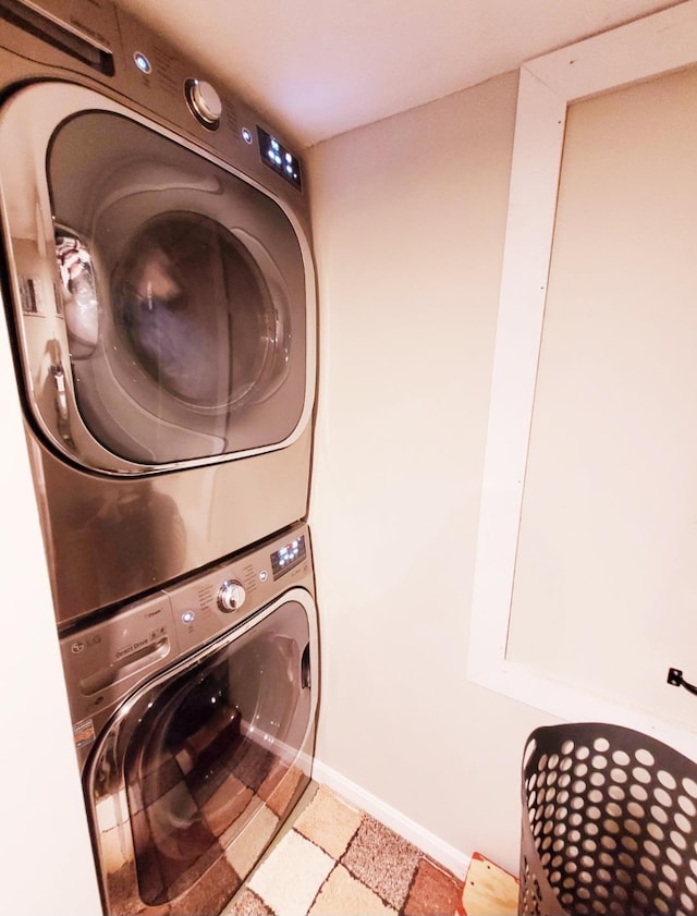 clothes washing area with laundry area, baseboards, and stacked washer and dryer