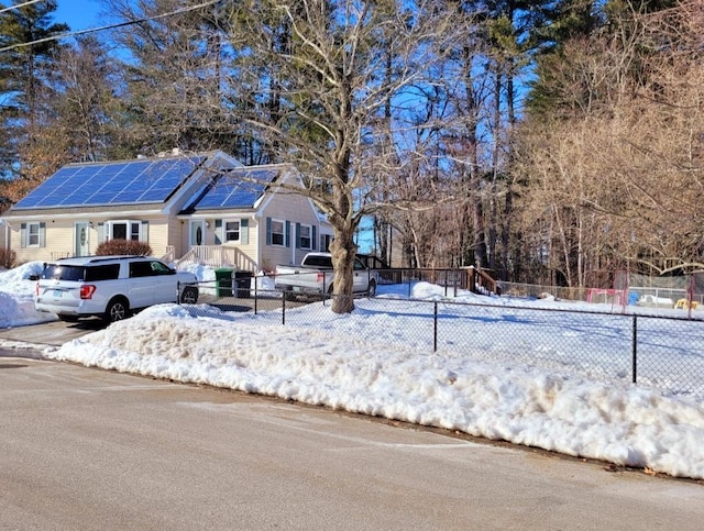 view of front of home with solar panels and fence