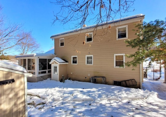 snow covered back of property with a sunroom