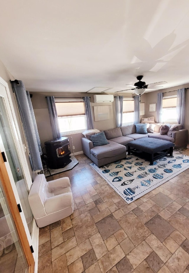 living area featuring a wealth of natural light, an AC wall unit, a wood stove, and stone finish floor