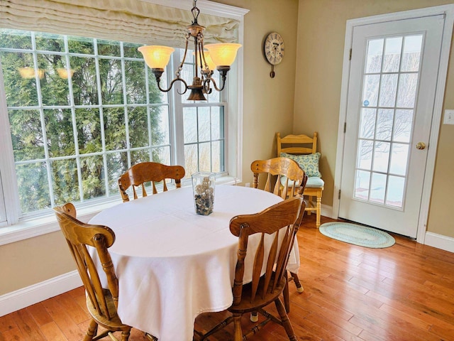 dining room featuring a chandelier, hardwood / wood-style floors, baseboards, and a healthy amount of sunlight