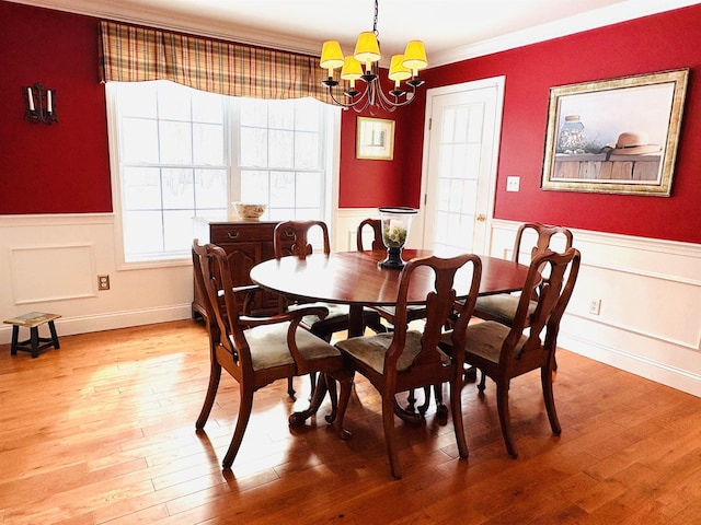 dining room featuring light wood-type flooring, wainscoting, and a notable chandelier