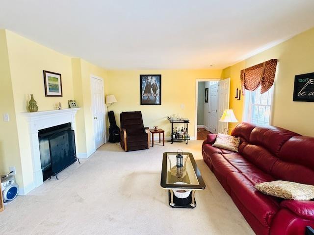 carpeted living area with a fireplace and baseboards