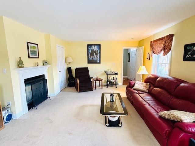 living room featuring carpet floors, a fireplace, and baseboards