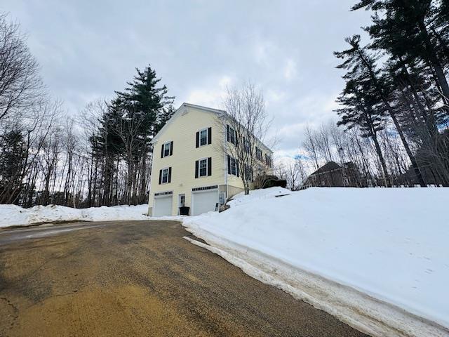 snow covered property featuring an attached garage