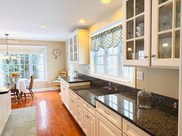 kitchen featuring baseboards, dark stone counters, wood-type flooring, decorative light fixtures, and recessed lighting