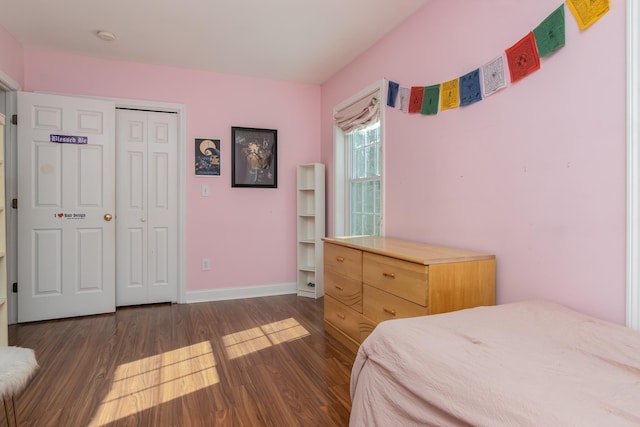 bedroom with a closet, wood finished floors, and baseboards