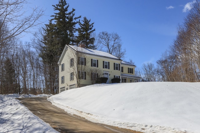 view of front of house with driveway, a chimney, and an attached garage