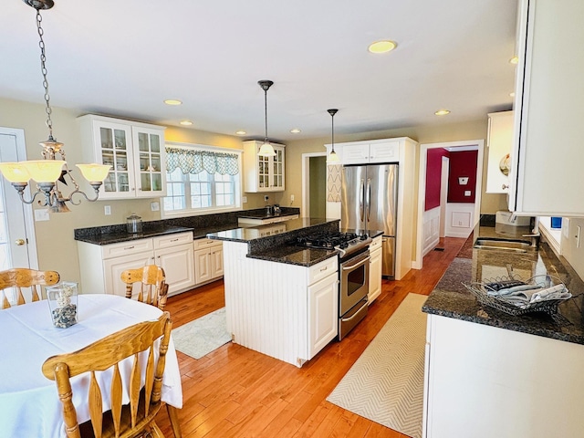 kitchen with white cabinets, light wood-style flooring, glass insert cabinets, a center island, and stainless steel appliances