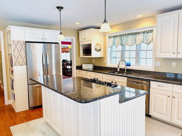 kitchen with hanging light fixtures, appliances with stainless steel finishes, a sink, and white cabinetry