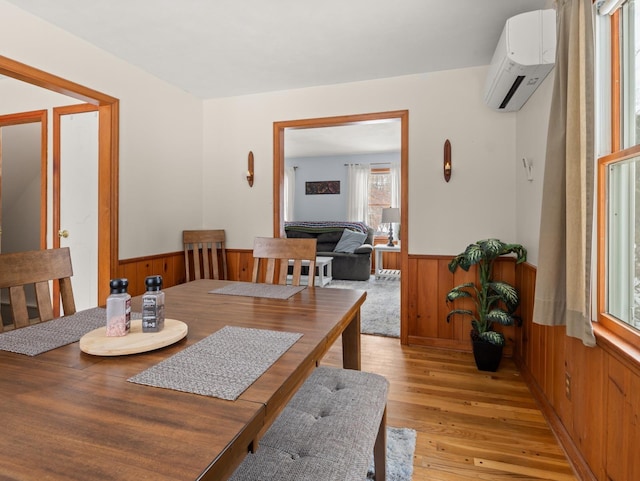 16 Ridge Rd, Essex, VT 05452 - dining area with wainscoting, a wall unit AC, wooden walls, and light wood finished floors