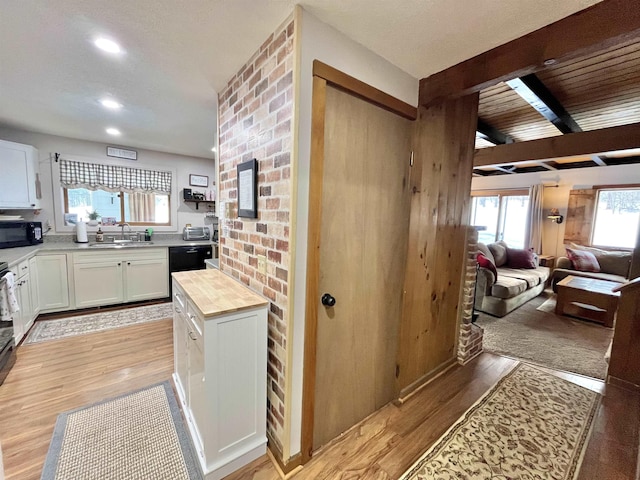 kitchen featuring black appliances, wood counters, white cabinetry, and a sink