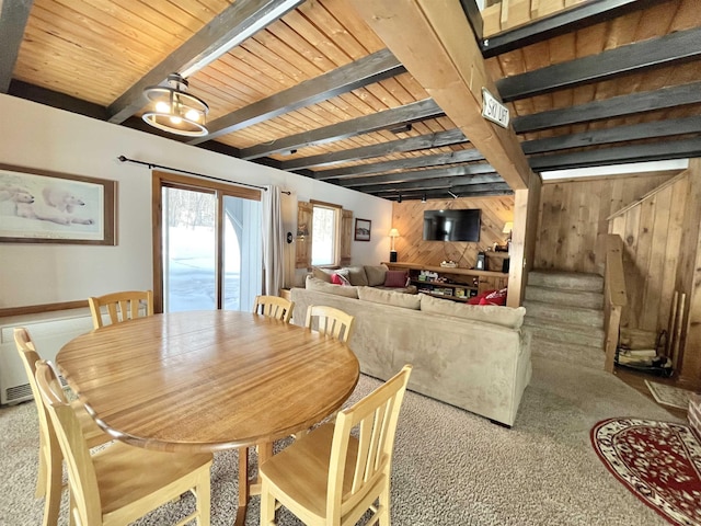 carpeted dining area featuring wood ceiling, wood walls, and beam ceiling