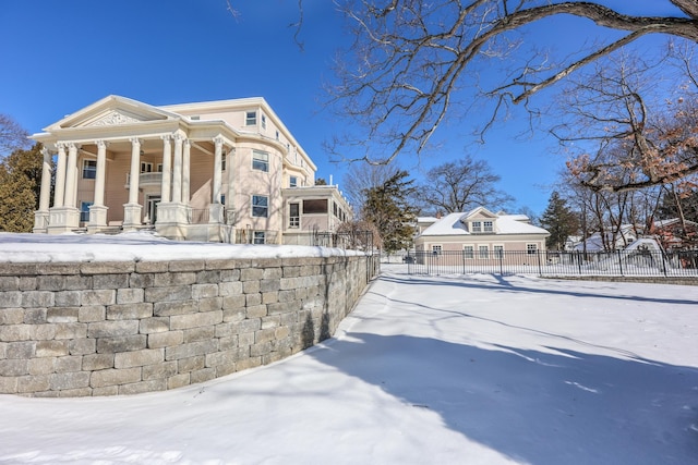 view of snow covered exterior with fence and a porch