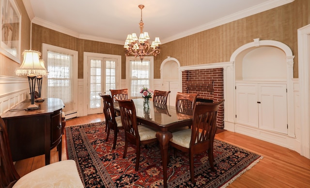 dining room featuring a baseboard heating unit, a wainscoted wall, a notable chandelier, and wallpapered walls