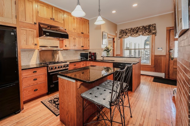 kitchen with a baseboard heating unit, freestanding refrigerator, wainscoting, ventilation hood, and high end range