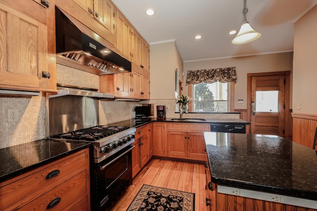 kitchen with under cabinet range hood, a wainscoted wall, a sink, gas range, and crown molding