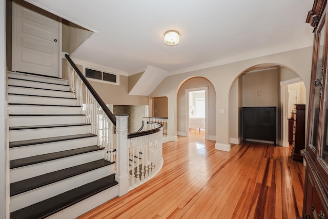 foyer featuring baseboards, light wood-type flooring, visible vents, and crown molding