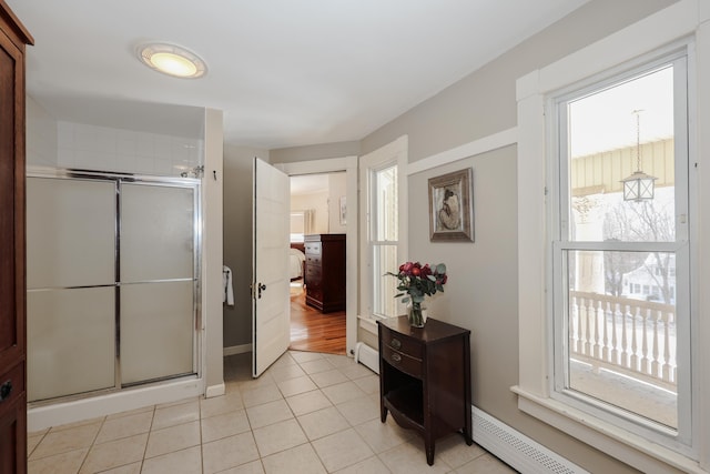 interior space with a baseboard heating unit, baseboard heating, a shower stall, and tile patterned floors