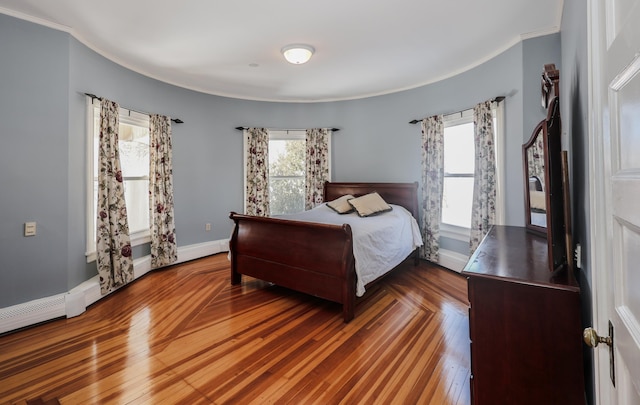 bedroom with ornamental molding, baseboards, and wood finished floors