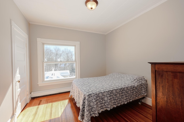 bedroom featuring a baseboard radiator, crown molding, and wood finished floors