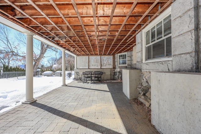 snow covered patio featuring outdoor dining space and fence