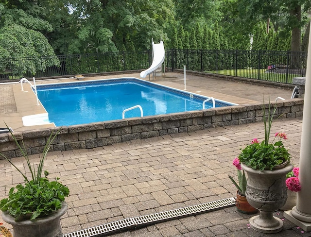 view of swimming pool featuring a fenced in pool, a water slide, fence, and a patio