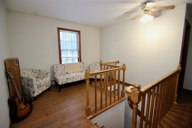 sitting room featuring hardwood / wood-style flooring, ceiling fan, and an upstairs landing