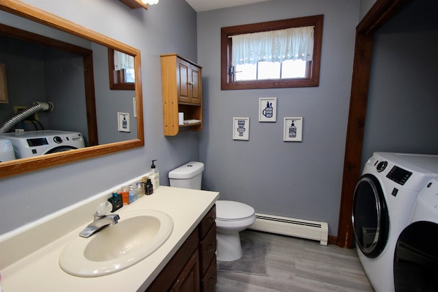 bathroom featuring toilet, wood finished floors, baseboard heating, vanity, and separate washer and dryer