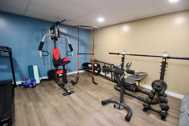 workout area featuring a drop ceiling, baseboards, and wood finished floors