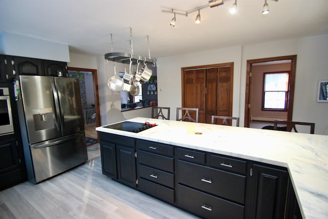 kitchen featuring a baseboard radiator, light stone countertops, stainless steel appliances, dark cabinetry, and light wood-style floors