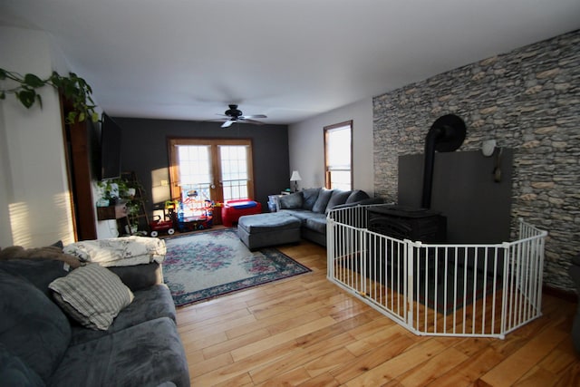 living area with a wood stove, a ceiling fan, and wood finished floors