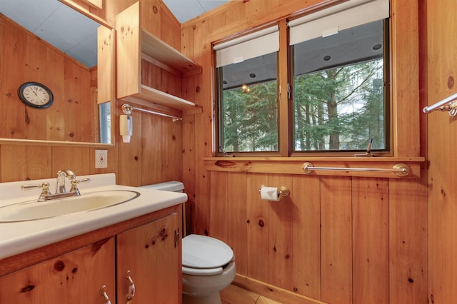 half bath featuring wooden walls, toilet, and vanity